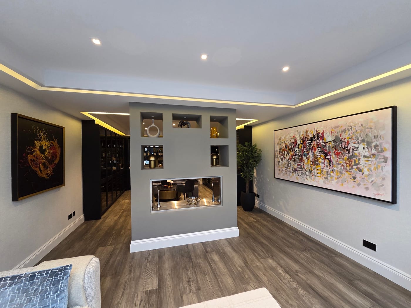 A client's lit hallway with a long gestural abstract in red, yellow and grey on one wall and a gold-on-black painting facing it